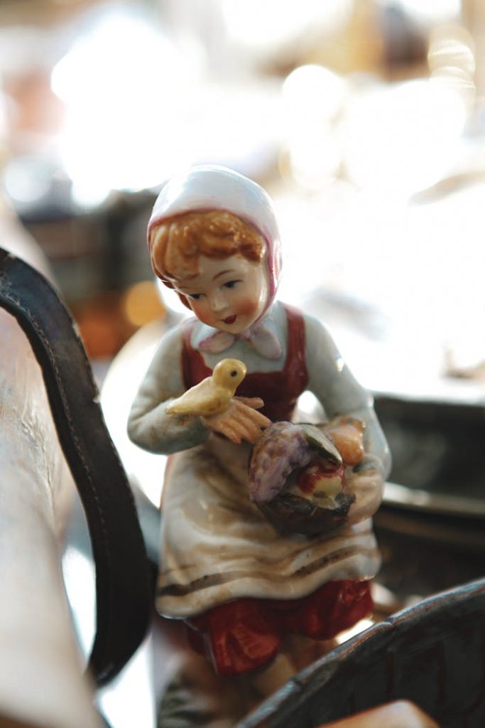 Close-up of a vintage doll figurine holding a bird, capturing a nostalgic, classic charm.