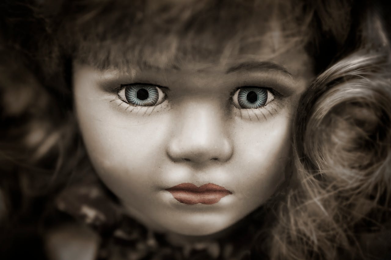 Intense close-up of a doll with an eerie expression and striking blue eyes, evoking mystery and unease.